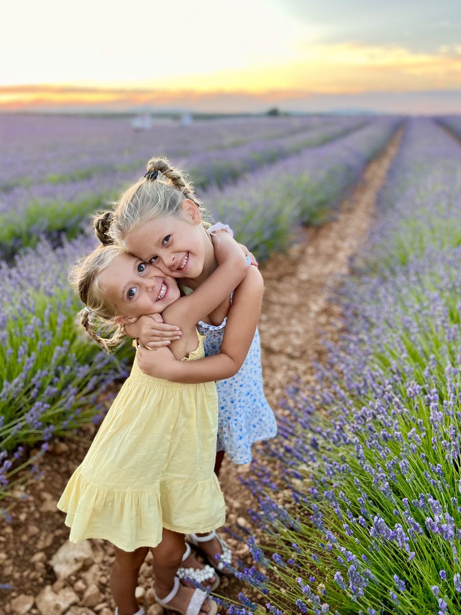Melanie's two daughters hugging in a field of lavender at sunset